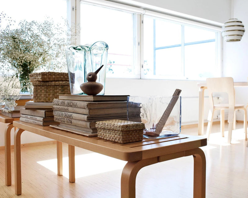 Natural wood slatted bench with two curved supports, standard coffee-table height.