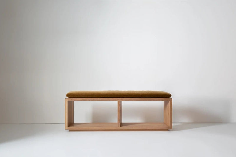 Wooden modular bench with cushioned top and three open cubbies, viewed from side.