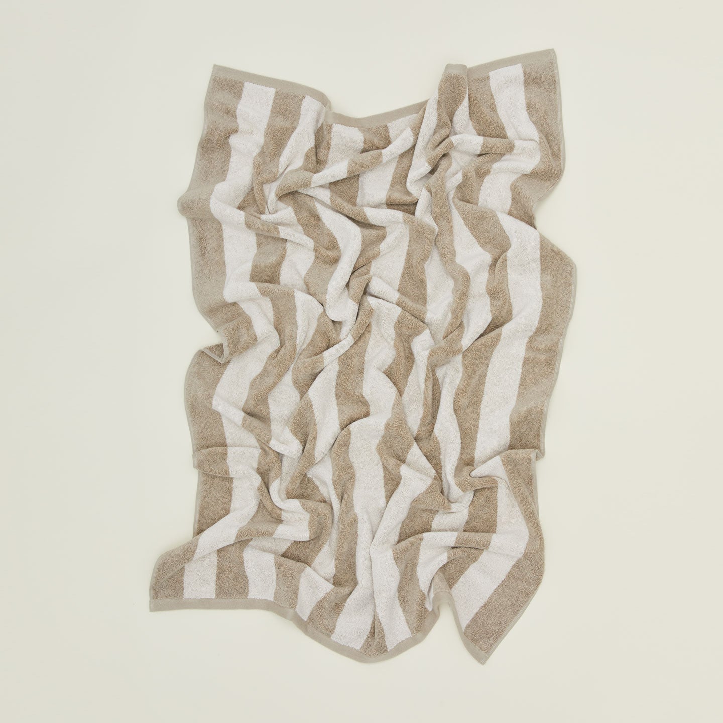 An overhead of a striped light grey and dark grey terry bath towel.