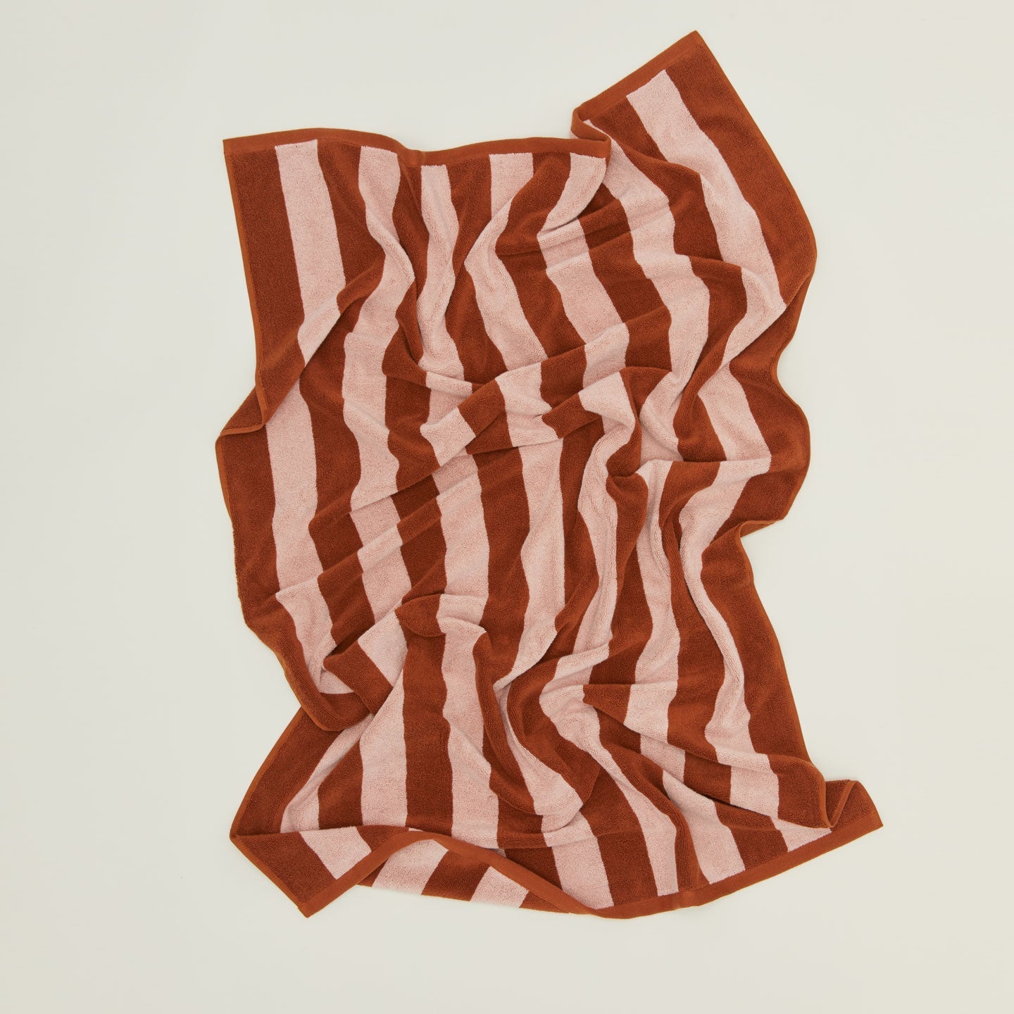 An overhead of a striped light grey and dark grey terry bath towel.