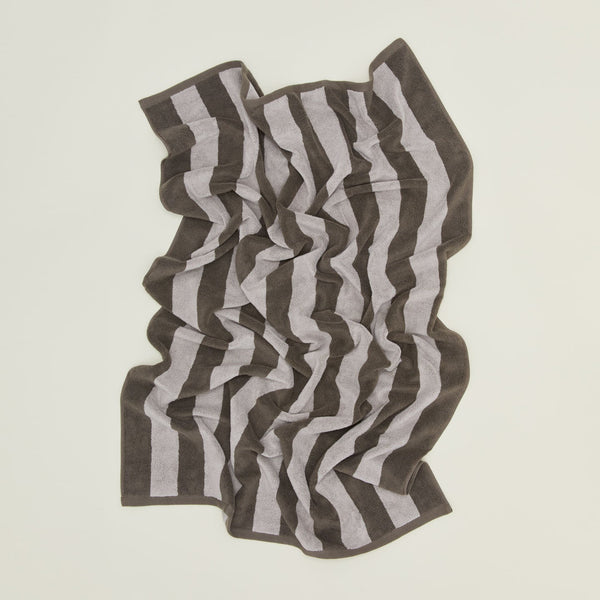 An overhead of a striped light grey and dark grey terry bath towel.