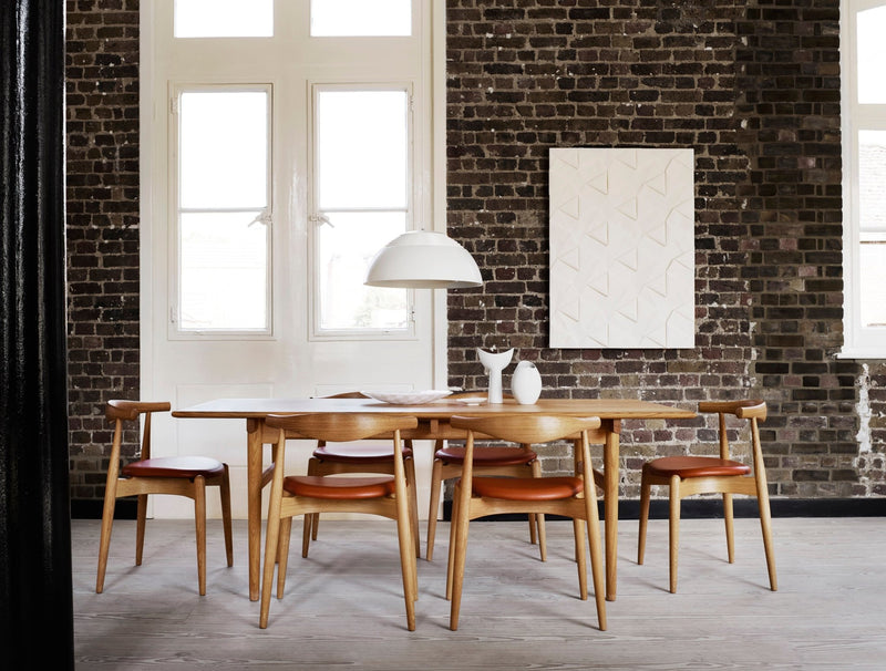Dining table with surrounding chairs in a well-lit modern room, focus on wood finish and design.