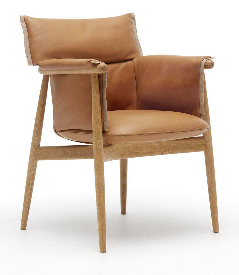 Natural oak wood armchair with tan leather cushions; light wood frame and rounded armrests in a modern style.