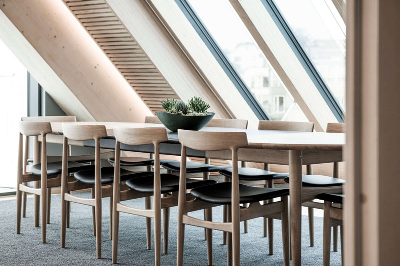 Large conference room with a long table, multiple chairs, and a wall-mounted screen, set for a meeting.