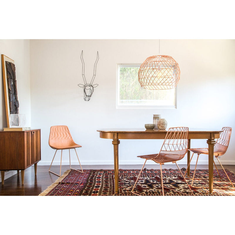 Close-up of white wire dining chair with slender legs and geometric back.