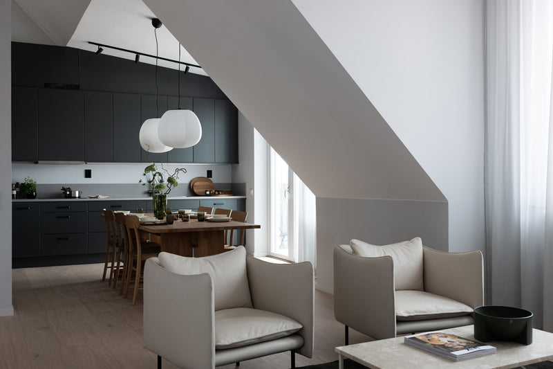 Contemporary dark gray and tan lobby seating with a long wooden table and black framed glass offices in background.