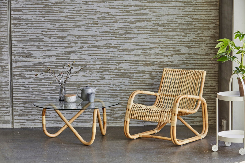 Coffee table with a wavy rattan base and a sleek, round glass top